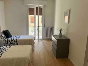 een slaapkamer met 2 bedden, een dressoir en een raam bij Pelusia apartment in Modena