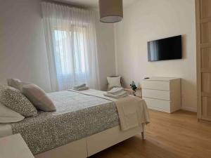 een witte slaapkamer met een bed en een televisie bij Pelusia apartment in Modena