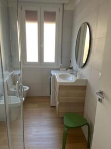 baño con lavabo, espejo y taburete en Pelusia apartment, en Módena