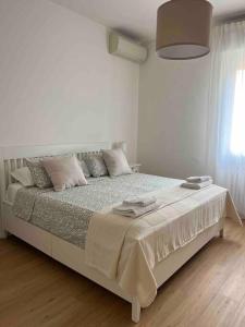 een witte slaapkamer met een groot bed met kussens bij Pelusia apartment in Modena