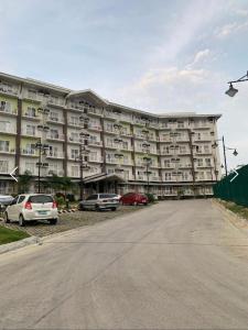 a large apartment building with cars parked in front of it at Seaview Amani Grand Resort Residences 3-5mins from airport in Mactan