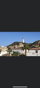 a view of a building with palm trees and a lighthouse at Casa Almanzora, apartamento de 1 dormitorio, wifi, parking gratuito in Zurgena