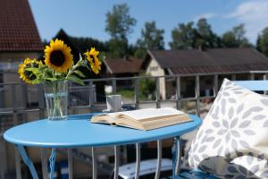 a blue table with a book and a vase of sunflowers at BeSSa Homes Haag 6 Personen 2 Schlafzimmer, 3 Betten, Balkon in Haag in Oberbayern