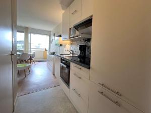kuchnia z białymi szafkami i piekarnikiem w obiekcie Studio cosy à Bénodet: plage, restos, thalasso à pied, balcon et parking privé - FR-1-481-135 w mieście Bénodet