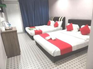 two beds in a hotel room with red and white pillows at Ar Rayyan Hotel in Tanah Rata