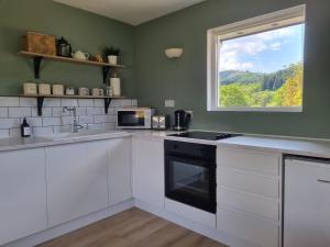 una cocina con armarios blancos y una ventana en The Apartment at Old Pier House en Fort Augustus