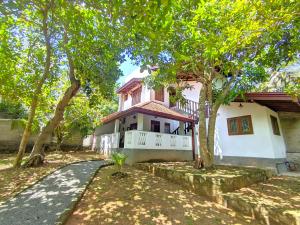 a pink and white house with trees in front of it at Calm Retreat in Mirissa