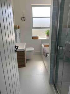 bagno con servizi igienici, lavandino e finestra di Hathaway Beach House a Southbourne