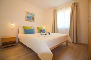 - une chambre dotée d'un grand lit blanc avec des oreillers verts et bleus dans l'établissement Ferienhaus-Lavanda-2, à Poreč