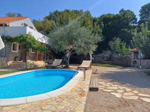 basen z 2 krzesłami i drzewo na dziedzińcu w obiekcie Holiday House Pulina w mieście Punat