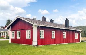 a red building with white windows on a green field at Lovely Home In Koppang With Kitchen in Koppang