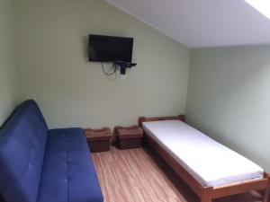 a small room with a blue couch and a tv at UROCZYSKO POD LASEM in Mikoszewo
