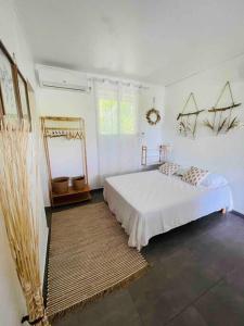 a white bedroom with a bed and a rug at La p’tite barque Antillaise in Deshaies