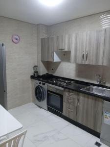 a kitchen with a stove and a sink and a dishwasher at Appart prestigieux+T bien équipé in Fès