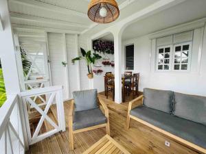 a porch with two chairs and a couch and a table at La p’tite barque Antillaise in Deshaies