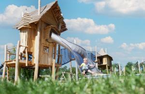 a young boy sitting on a slide at a playground at Familievakantiepark Krieghuusbelten in Raalte