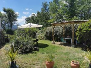 un jardín con sombrilla, mesa y sillas en Entre Ventoux et Luberon, appartement dans maison. en Malemort-du-Comtat