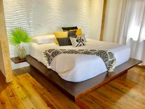a large white bed in a room with a wooden floor at Turtle Beach Sanctuary, Utila in Utila