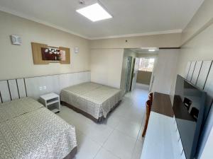 a hotel room with two beds and a television at Spazzio Diroma com acesso ao Acqua Park todos os dias in Caldas Novas