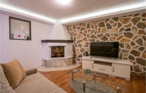 sala de estar con TV y pared de piedra. en Stunning Home In Makarska With 1 Bedrooms And Wifi, en Makarska