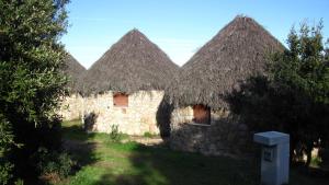 a group of three stone buildings with thatched roofs at B&B Supramonte in Orgosolo