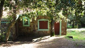 a stone house with a red door and two trees at B&B Supramonte in Orgosolo