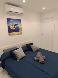 a bedroom with a blue bed with two pillows at 54 ONE by RW San Julian's in St. Julianʼs