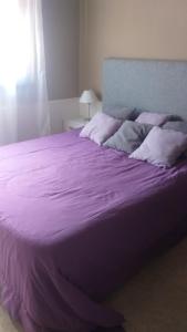 a large bed with purple sheets and pillows at casa lucia in La Falda