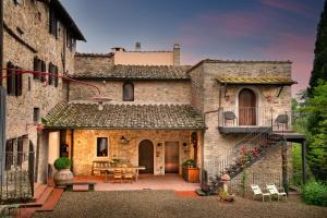 uma antiga casa de pedra com um pátio e uma mesa em La Pensione di Vignamaggio em Panzano