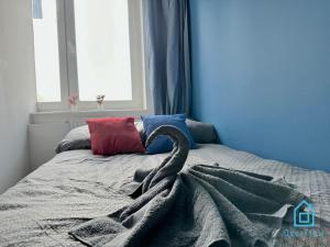 a bed with a gray blanket and a window at Colourful Room in Gdańsk