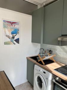 una cucina con lavatrice e lavandino di 2 pièces cocooning près du port/gare riquier a Nizza