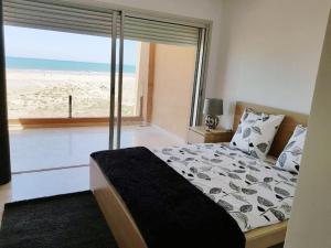 Plage de rêve في Agadir nʼ Aït Sa: غرفة نوم بسرير مع اطلالة على الشاطئ