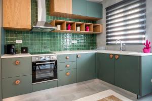 una cucina con armadi verdi e lavandino di Anna Suites a Città di Kos