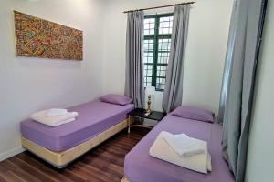 two beds in a room with purple sheets and a window at Forest Valley Homestay Bungalow for Family/Group Staycation/Gathering in Cheras