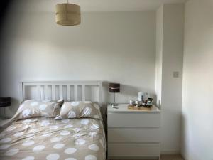 a white bedroom with a bed and a night stand at Withy Farm in Canterbury