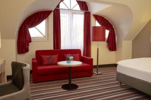 a living room with a red chair and a table at Sunday Hotel Stade Herzog Widukind in Stade +25 photos