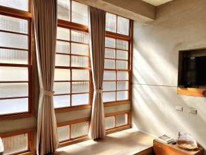 a room with a window with curtains and a tv at Loku. Tainan in Tainan