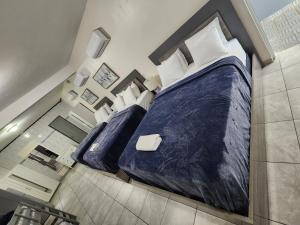 a bedroom with two beds with blue sheets and white pillows at The Village Inn in Carolina