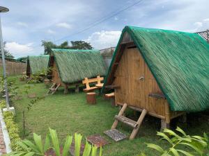 a group of huts with a table and a bench at Unlimited Pax Bale Kubo-inspired Accommodation in Tarlac
