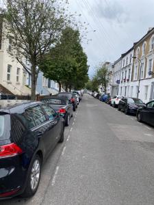 een rij auto's geparkeerd aan de kant van een straat bij The London apartment in Londen