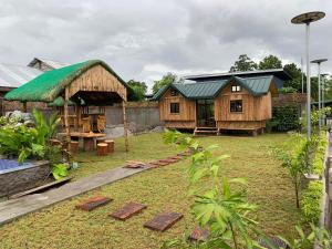 een huis met een groen dak in een tuin bij Unlimited Pax Bale Kubo-inspired Accommodation in Tarlac