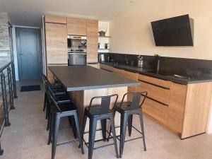 a kitchen with a large island with black bar stools at Très bel appart avec vue 6 personnes Alpe d Huez in LʼHuez +14 photos
