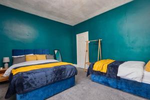 two beds in a room with blue walls at Stylish Comfortable Home With Parking in Redcar