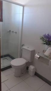 a white bathroom with a toilet and a shower at Suíte Delicada Centro Búzios in Búzios