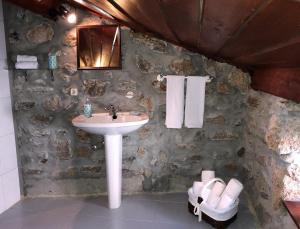 a bathroom with a sink and a stone wall at Casa do Barrosinho in Penedones