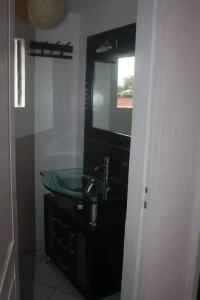 ein Badezimmer mit einem Glaswaschbecken und einem Spiegel in der Unterkunft Appartements Andrian Location in Antananarivo