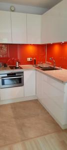 a kitchen with white cabinets and an orange wall at Apartament Centrum przy Parku Zdrojowym in Nałęczów