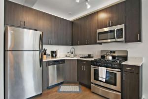 una cocina con electrodomésticos de acero inoxidable y armarios de madera en 1BR Prime and Comfy Apt with In-Unit Laundry - Lake 302 en Chicago