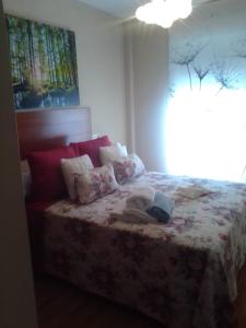 a bedroom with a bed with a flowered blanket and a window at O Xuncal in Barreiros