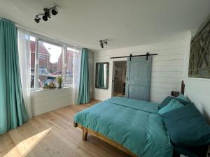 a bedroom with a bed with blue sheets and a window at The Seahorse Beach House in Egmond aan Zee